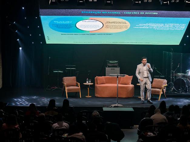 Gustavo Coelho no palco diante de uma apresentação sobre gestão